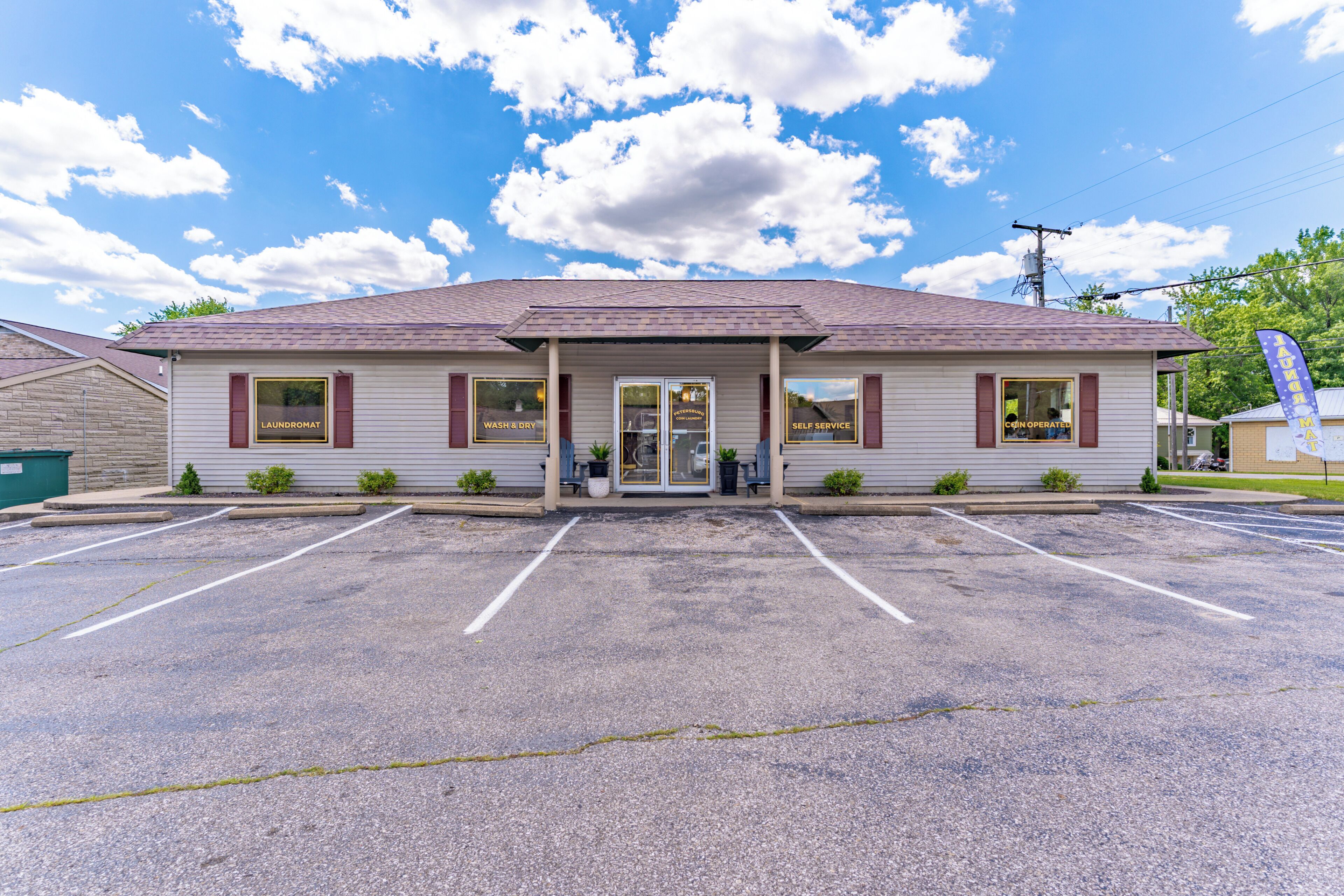 A single-story building with a flat roof, a front entrance, and a parking lot in front.