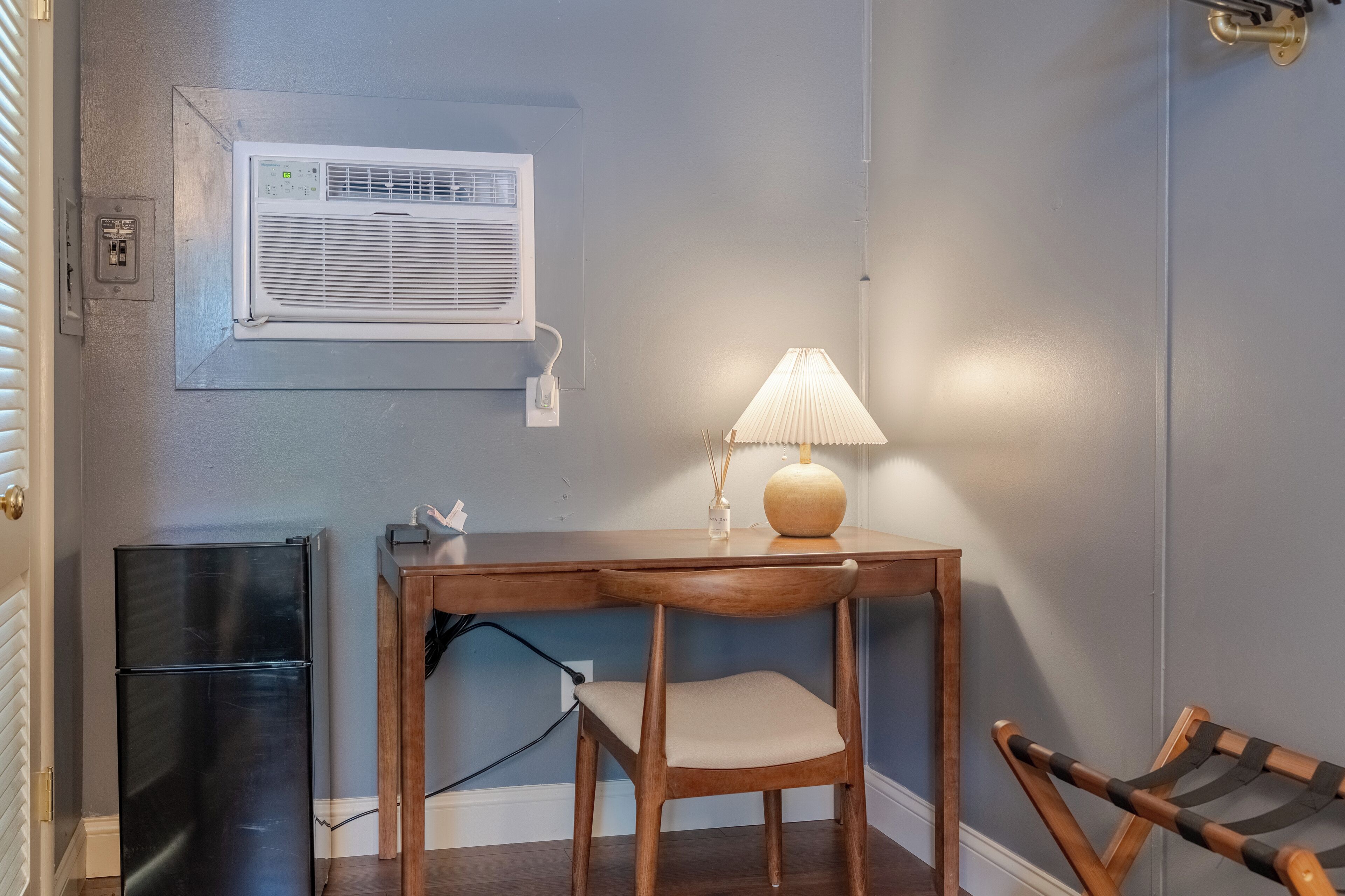 A compact room with a wooden table, a chair, a lamp, and a small black cabinet.