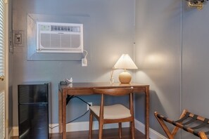A compact room with a wooden table, a chair, a lamp, and a small black cabinet.