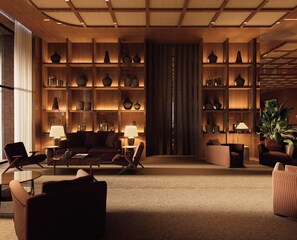 A modern interior with a central seating area, wooden shelving with decorative items, and a large plant. - Fasano Peninsula (Punta del Este)