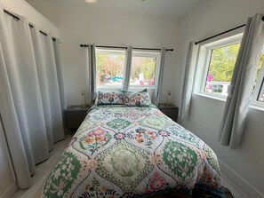 Ein Schlafzimmer mit einem Bett, zwei Fenstern und Vorhängen.