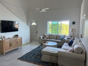Un salon spacieux équipé d’un téléviseur à écran plat, d’un ensemble de canapés, d’une table basse et d’un ventilateur de plafond.