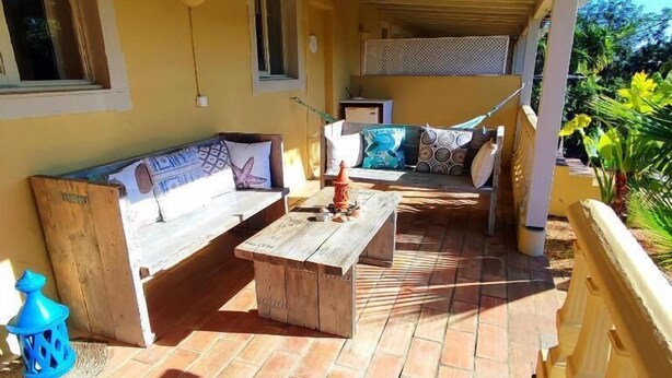 An outdoor patio with a wooden bench, a sofa, and a hammock.