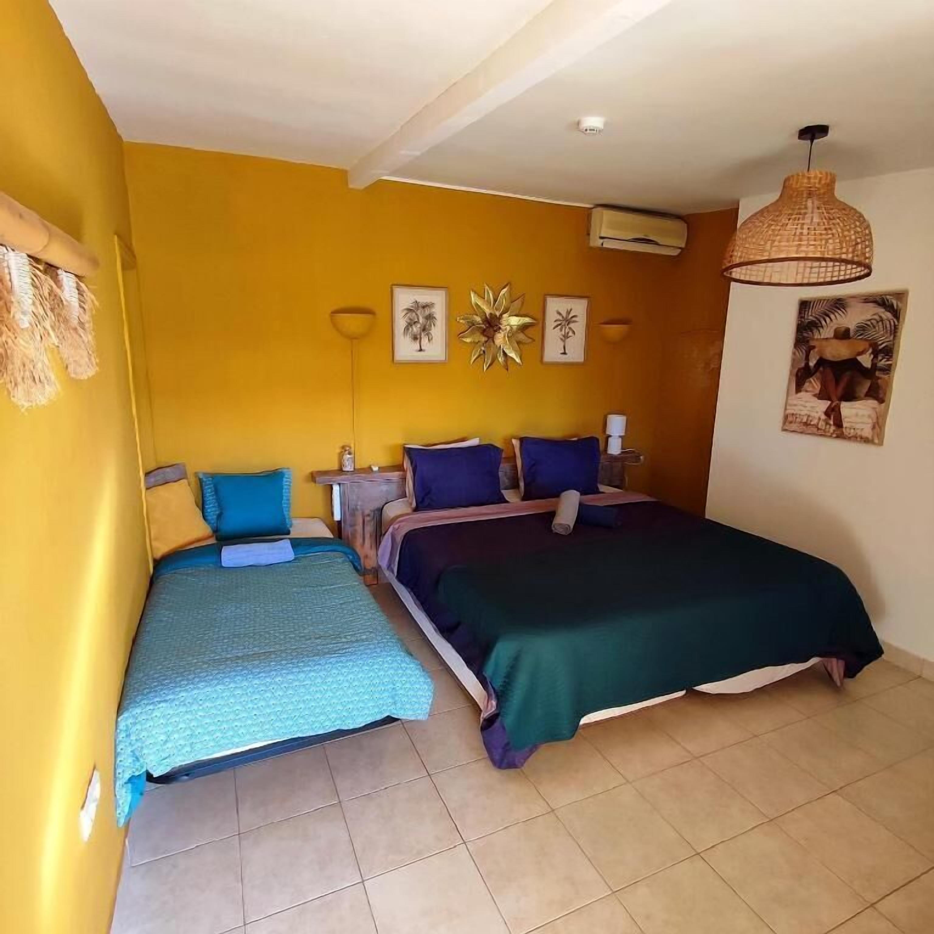 Habitación con dos camas, ventilador de techo y aire acondicionado instalado en la pared.