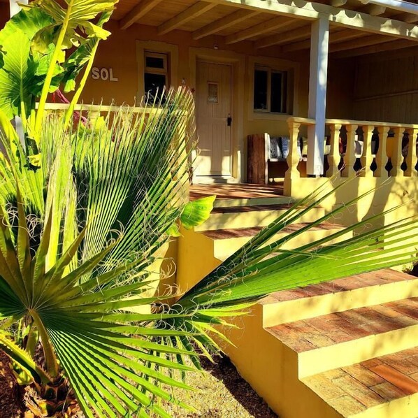 A yellow building with a porch and steps leading to a door.