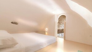 Une chambre à coucher avec un lit, une table de chevet et une fenêtre donnant sur l’extérieur.