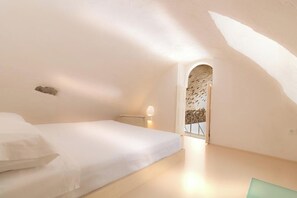 Een slaapkamer met een bed, een nachtkastje en een raam met uitzicht.