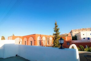 A building with arched windows and a white wall in the foreground. - Tritiani Traditional House (Messaria)