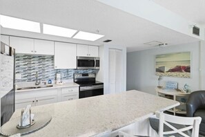 A modern kitchen with white cabinets, a granite countertop, and a microwave. - Excellent 1-bedroom 1-bath condo with AC in Indian Rocks Beach (Indian Rocks Beach)