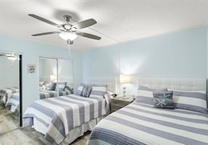 Ein Schlafzimmer mit zwei Betten, einem Deckenventilator, einem Spiegel und Nachttischen.