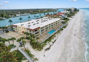 Ein Strandhotel mit mehreren Balkonen, einem Pool und Blick auf das Meer und den Yachthafen.