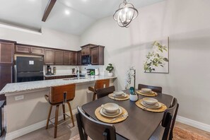 A modern kitchen with dark wood cabinets, a granite countertop, and a stainless steel refrigerator.