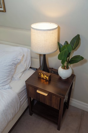 A bedside table with a lamp, a digital clock, and a potted plant. - Gorgeous 3 bed 2 bath property with 2 car garage (Wichita)
