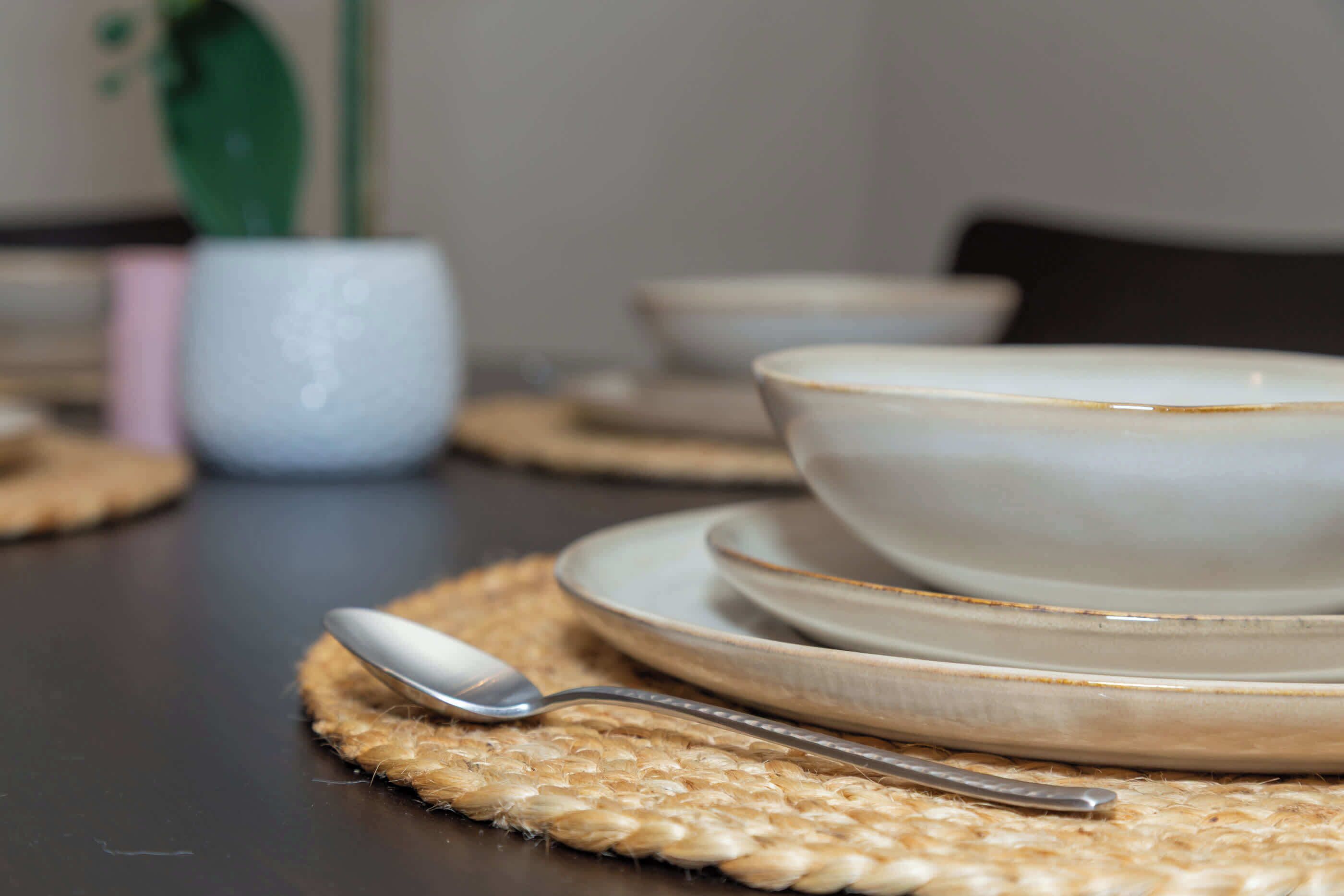 Een eettafel met een bord, een kom en een lepel.