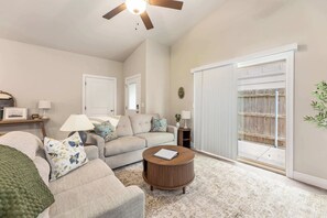 A living room with a sofa, a coffee table, and a ceiling fan. There is a door and a window with blinds. - Beautiful 3 bed 2 bath property with 2 car garage (Wichita)