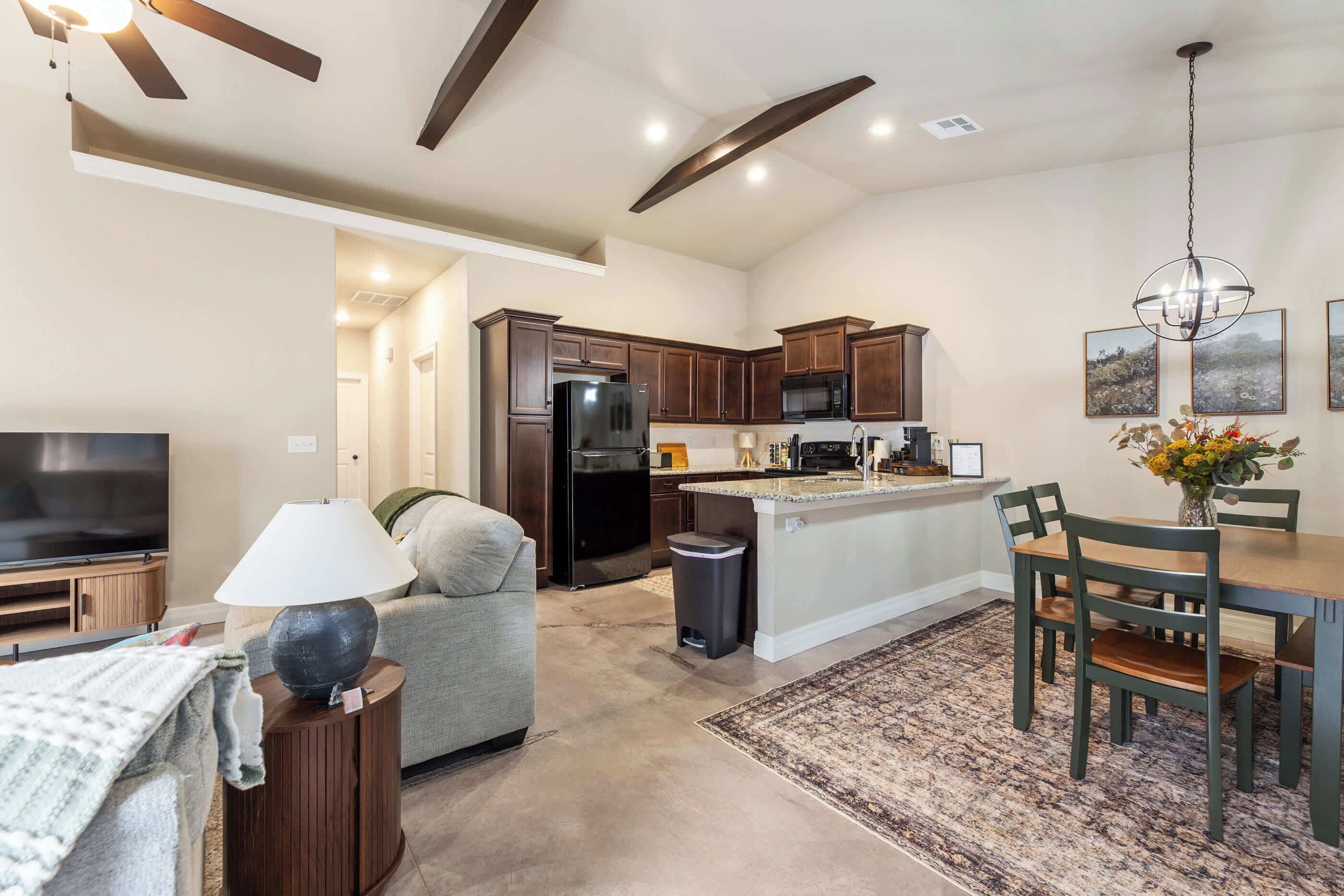 A modern kitchen with dark wooden cabinets, a black refrigerator, and a microwave.