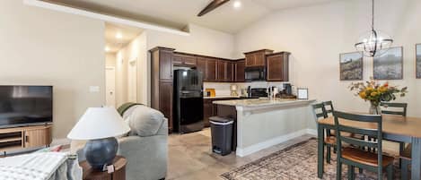 A modern kitchen with dark wooden cabinets, a black refrigerator, and a microwave.