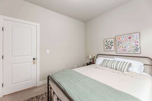 A bedroom with a bed, a nightstand, a lamp, and two framed botanical prints on the wall. - Beautiful 3 bed 2 bath property with 2 car garage (Wichita)