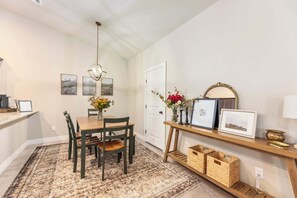 A dining area with a wooden table and chairs, a chandelier, framed artwork on the walls, and a small shelf with decorative items. - Beautiful 3 bed 2 bath property with 2 car garage (Wichita)
