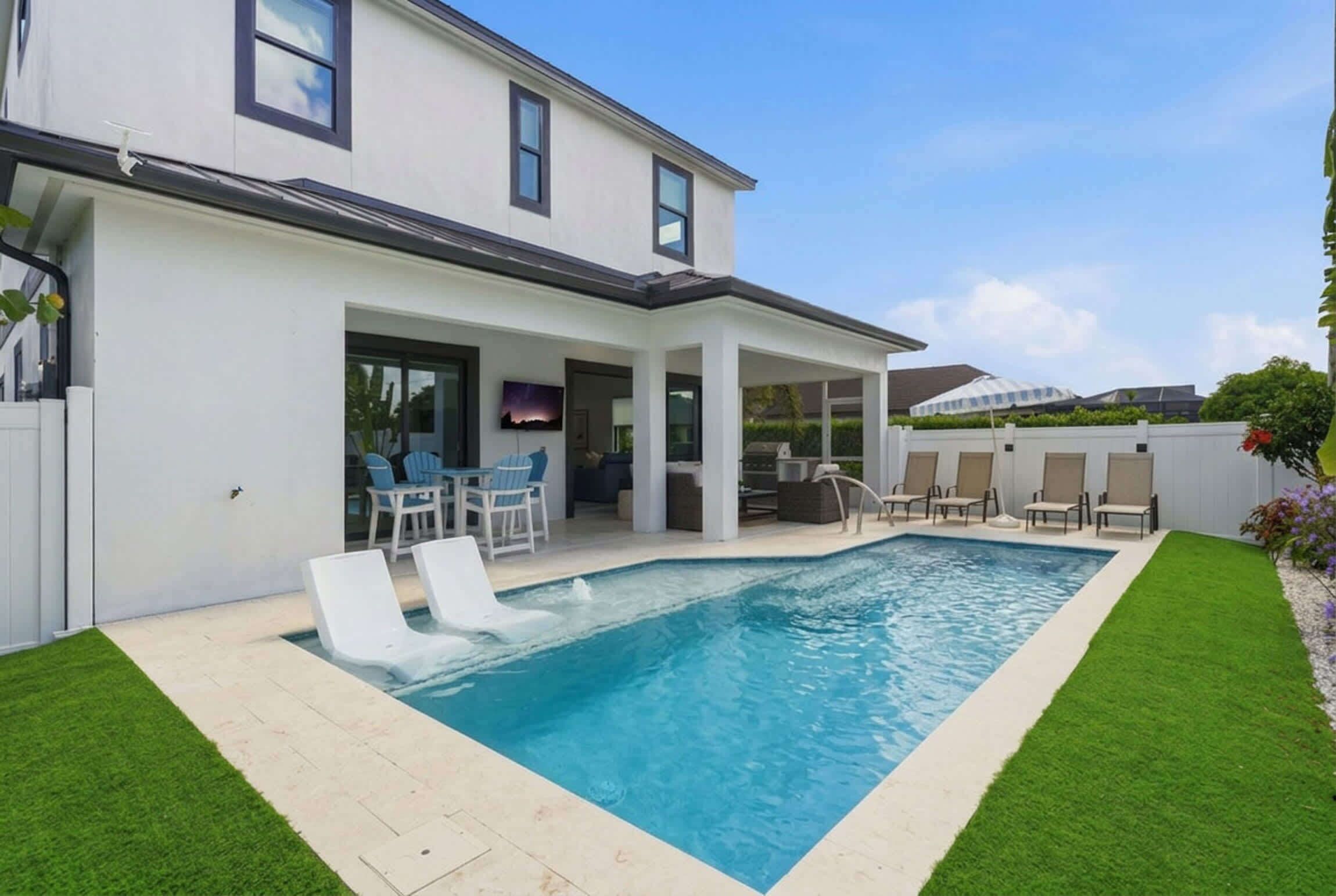 A modern house with a swimming pool, outdoor seating, and a covered patio area.