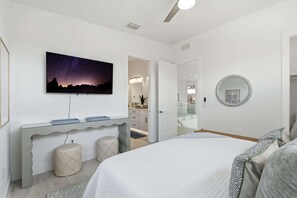 A bedroom with a bed, a night sky mural, a desk with storage, a round mirror, and a bathroom visible through an open door. - Brand-New Luxury Pool Home Steps from the Gulf (Naples)