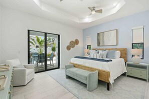 Ein modernes Schlafzimmer mit einem großen Bett, einer Sitzecke und Blick ins Freie.