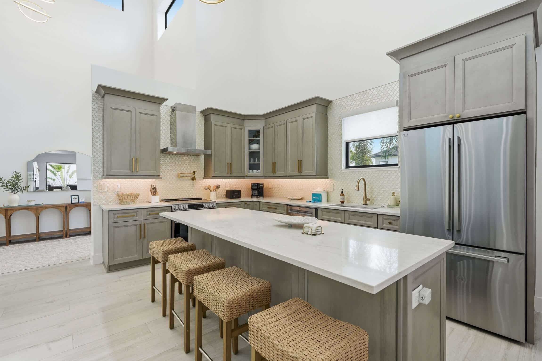 A modern kitchen with a large island, stainless steel appliances, and a view to the outdoors.