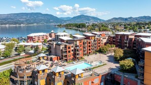 Un hotel de varios pisos con balcones, piscina y vistas a un lago y montañas.