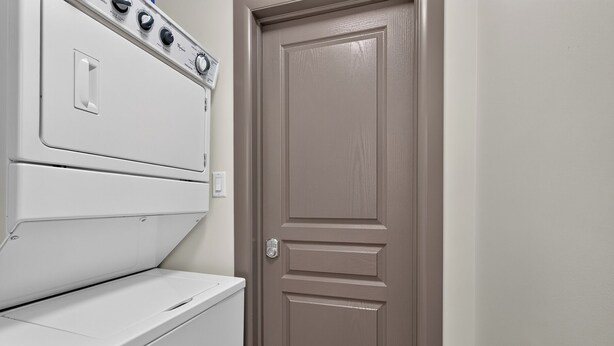 Un lavadero con una secadora blanca y una puerta color beige.