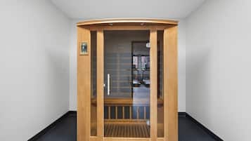 A wooden sauna with a glass door, a control panel, and a bench inside.