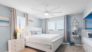 A bedroom with a bed, a nightstand, a dresser, a ceiling fan, and a window with curtains. - Santa Rosa Dunes 321 (Pensacola Beach)