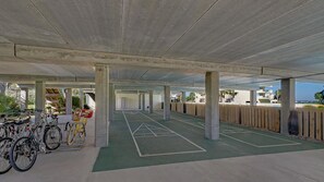 An indoor parking area with concrete pillars, a green bike lane, and a wooden fence. - Santa Rosa Dunes 321 (Pensacola Beach)
