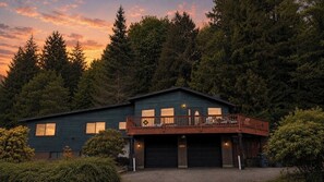 A two-story house with a balcony, surrounded by dense forest. - Private Beach Access • Ocean & Mountain Views • Near Olympic National Park (Port Angeles)
