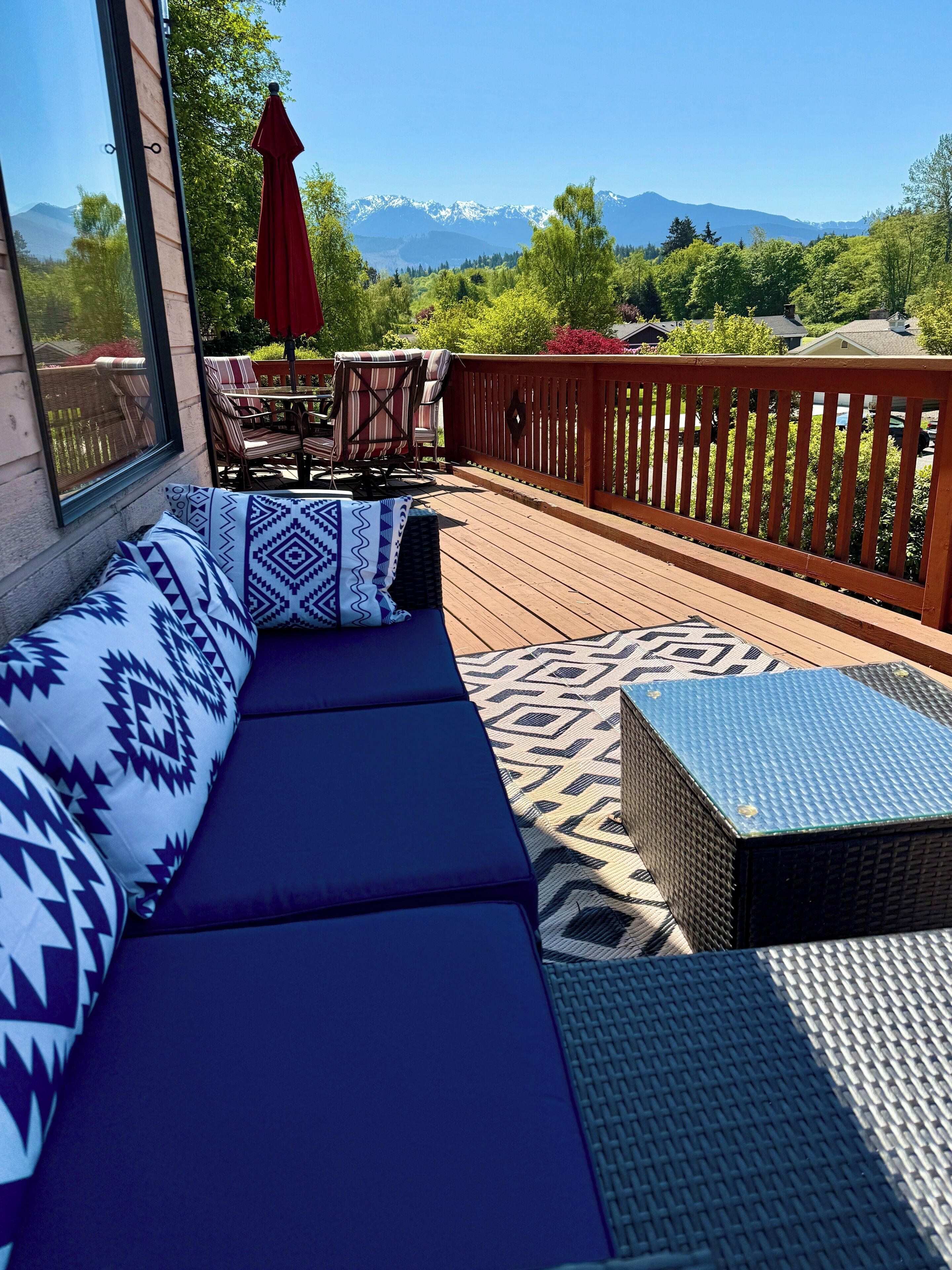 A deck with a sofa, chairs, and a table, overlooking a mountainous landscape.