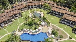 Un complexe hôtelier comprenant plusieurs bâtiments de style bungalow, une piscine centrale et des jardins bien entretenus.