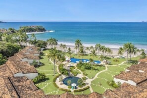 A resort with multiple bungalow-style buildings, a central pool area, and a beach view. - Spacious condo in enchanting Playa Flamingo - the most glorious views & 2 pools! (Playa Flamingo)