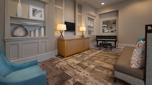A living room with a blue armchair, a beige sofa, a wooden console table with lamps, a piano, and a television on the wall. - Marriott's OceanWatch Resort : 2 Bedroom, 7 nights, Ocean Side. (Myrtle Beach)