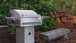 A portable grill with a control panel, set against a backdrop of greenery and wooden picnic tables. - Marriott's OceanWatch Resort : 2 Bedroom, 7 nights, Ocean Side. (Myrtle Beach)