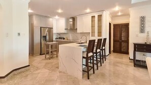 Une cuisine moderne dotée d’un îlot central, de meubles de rangement intégrés et d’un coin repas avec des chaises.