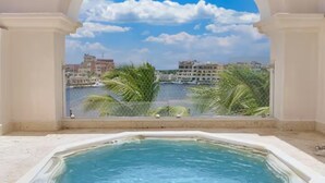 Un bain à remous dans une pièce offrant une vue sur la ville et les palmiers.