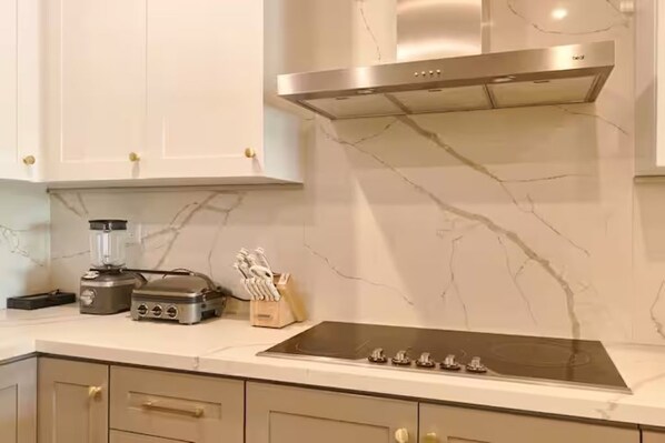 A kitchen with a marble backsplash, a stainless steel range hood, a built-in stove, and a blender on the counter. - Luxury Penthouse in Cap Cana Marina with Jacuzzi (Punta Cana)