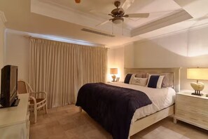 A hotel room with a bed, a television, a chair, a nightstand, and a ceiling fan. - Luxury Penthouse in Cap Cana Marina with Jacuzzi (Punta Cana)
