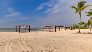 Une plage avec des structures en bois et des palmiers.