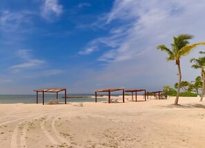 Ein Strand mit Holzgebäuden und Palmen.
