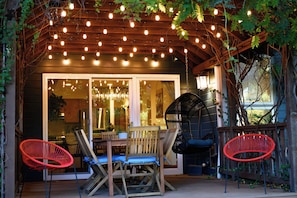 Eine Terrasse im Freien mit Holztisch und -stühlen, einem Hängesessel und Lichterketten.