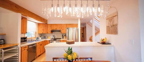 A modern kitchen with wooden cabinets, a central island, and a hanging light fixture.
