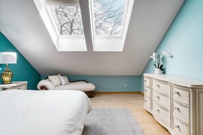 A bedroom with a sloped ceiling, skylights, a bed, a nightstand, a dresser, and a potted plant. - Serene + Spacious Boulder Oasis | Sleeps 10 | 30+ (Boulder)