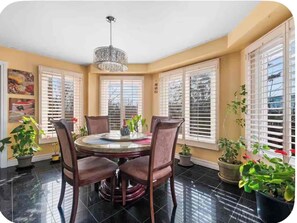 A dining area with a round table, four chairs, a chandelier, and large windows with blinds. - Stylish Private Room | Free Parking | Fast WiFi | Great Location (Pickering)