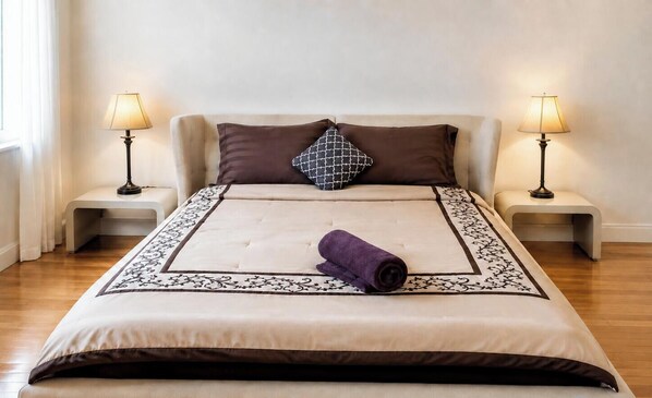 A neatly made bed with a patterned bedspread and a rolled towel, flanked by two bedside lamps on matching nightstands. - Stylish Private Room | Free Parking | Fast WiFi | Great Location (Pickering)