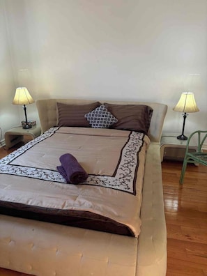 A neatly made bed with a patterned bedspread, two pillows, and a folded towel. There are two bedside lamps on either side of the bed.
